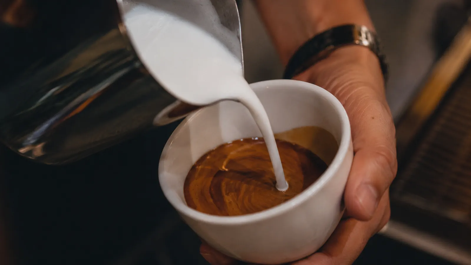 Steamed milk being poured into an espresso shot to make a latte, showing milk texture close-up