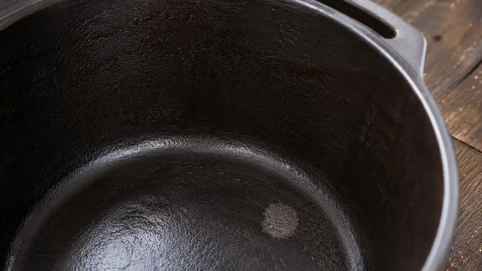 Close-up of cast iron seasoning layers showing dark patina on the inside of the Lodge Dutch oven